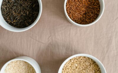 Top view of four ceramic bowls filled with different types of rice on a neutral background.