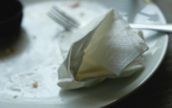A close-up of an empty plate with a crumpled napkin and fork, creating a post-meal scene.