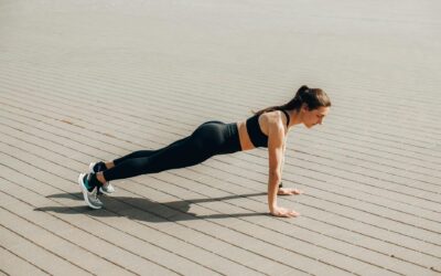 Woman doing push-ups outdoors in activewear, promoting fitness and healthy lifestyle.