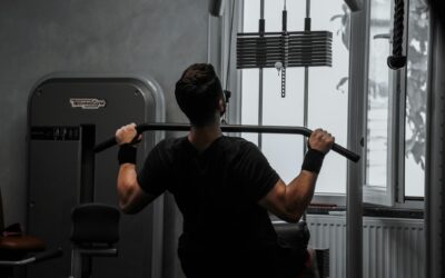 A man working out on a lat pulldown machine in a gym, focusing on strength building.