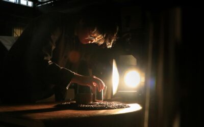 Artisan intensely focuses on crafting in dramatic lighting, highlighting the dedication and skill involved in craftsmanship.