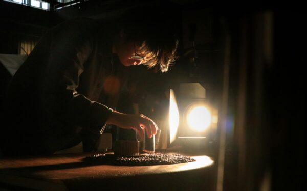 Artisan intensely focuses on crafting in dramatic lighting, highlighting the dedication and skill involved in craftsmanship.