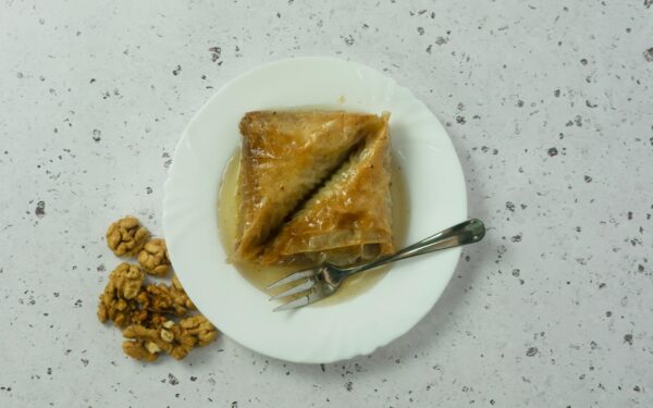 Tasty Serbian baklava with walnuts, drenched in honey syrup on a white plate. Perfect dessert indulgence.