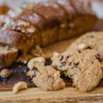 Close-up of sliced bread with nuts and delicious cookies on a rustic wooden board.