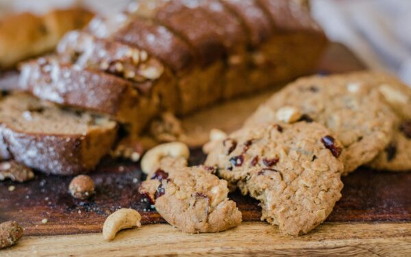 Close-up of sliced bread with nuts and delicious cookies on a rustic wooden board.