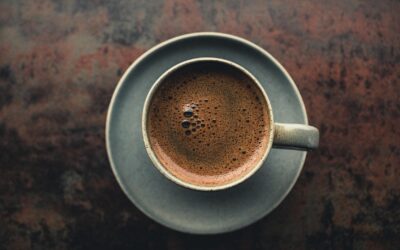 Top view of a hot espresso in a rustic ceramic mug on a dark textured surface.
