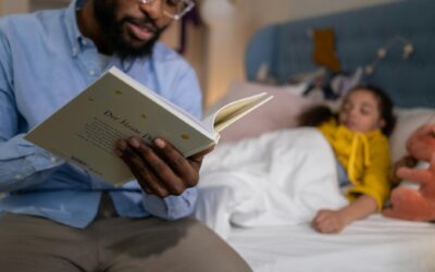 A father reading a bedtime story to his daughter, who is lying in bed, creating a warm and cozy atmosphere.