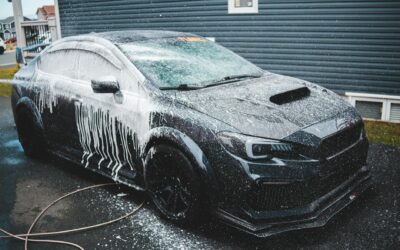 Black expensive tuned sports car under car wash next to cottage in daytime
