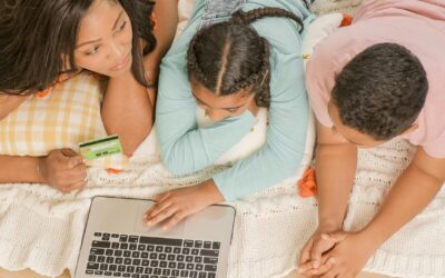 Mother and children shopping online together at home on a laptop.