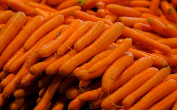 Close-up of vibrant orange carrots in a market setting, highlighting freshness and health.