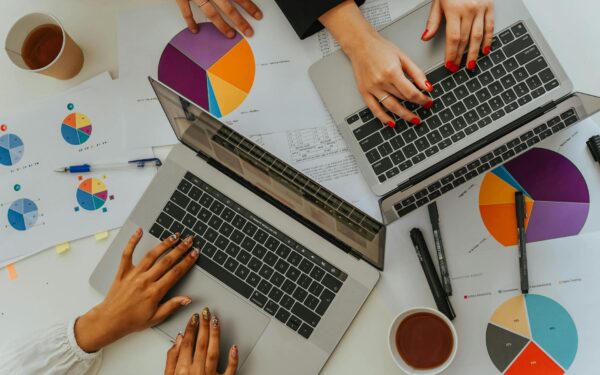 Overhead view of a team analyzing graphs and charts using laptops at a meeting.