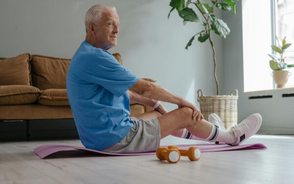 Elderly man exercising at home with yoga and weights for a healthy lifestyle.