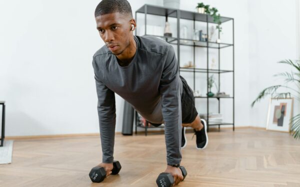 Man performing push-up exercises with dumbbells indoors. Fitness and healthy lifestyle concept.