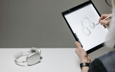 Artist sketching headphones on a tablet with stylus, creating digital art.