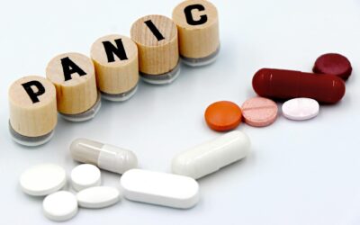 Assorted pills arranged beside wooden tiles spelling 'PANIC', symbolizing anxiety treatment.