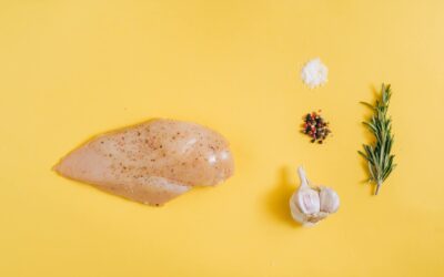 Chicken breast with garlic, rosemary, and spices on a yellow background.