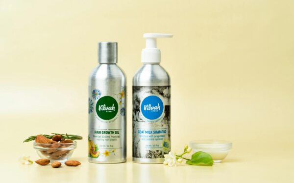 Natural hair care products featuring goat milk shampoo and hair growth oil on a yellow background.