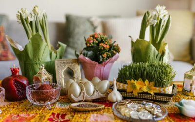 A vibrant arrangement of Nowruz haft-seen elements featuring greenery, flowers, and traditional items.