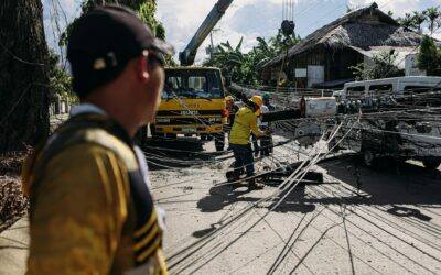 Utility workers assess and fix downed power lines on a sunny day, ensuring safety and service restoration.