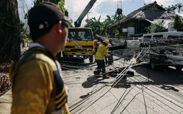 Utility workers assess and fix downed power lines on a sunny day, ensuring safety and service restoration.
