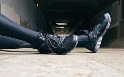 Close-up of a runner's legs in athletic wear resting in an urban tunnel.