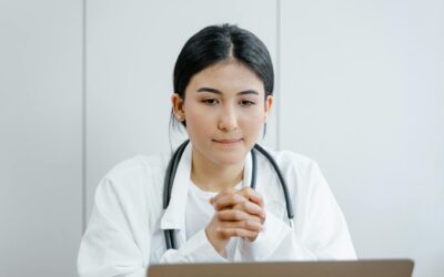 Young female doctor in white coat consulting online with stethoscope indoors.