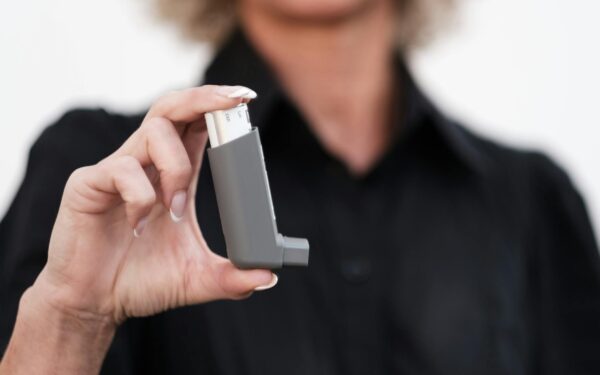 Close-up of a woman holding an asthma inhaler, focusing on respiratory health solutions.