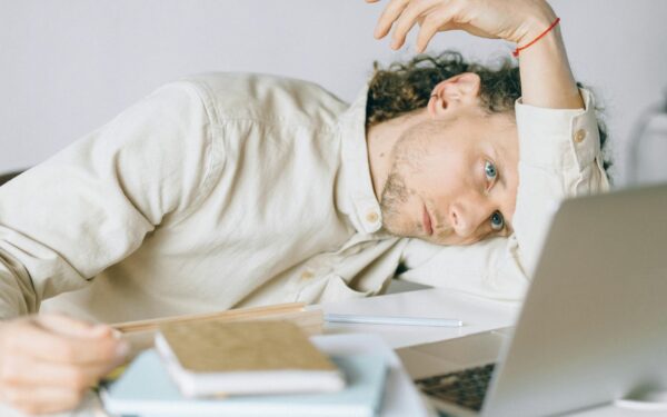 A tired Caucasian man at a desk, showing signs of exhaustion and stress, exemplifying workplace burnout.