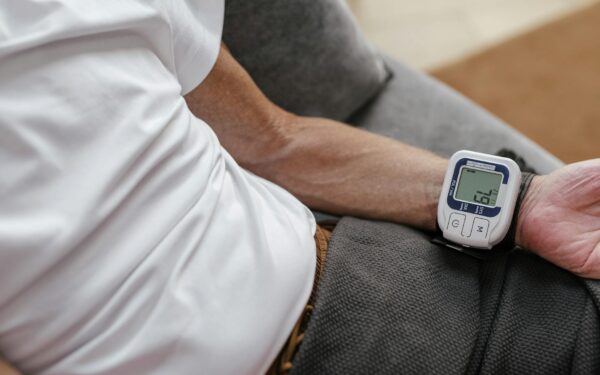 Adult man using a wrist blood pressure monitor to measure blood pressure at home.