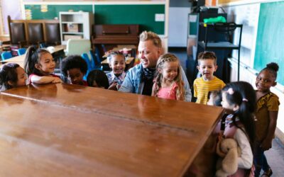 Kindergarten children gathered around a teacher, engaging in cheerful learning activities in a vibrant classroom.