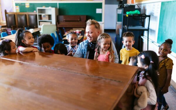 Kindergarten children gathered around a teacher, engaging in cheerful learning activities in a vibrant classroom.