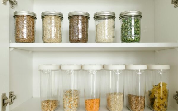 Neatly arranged pantry showcasing grains in glass jars and dry goods in plastic containers.