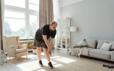 Man performing a stretching exercise in a sunlit living room, embracing a healthy lifestyle.