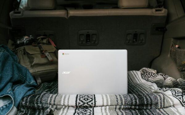 Laptop setup in a car trunk with cozy blanket for remote work travel ease.
