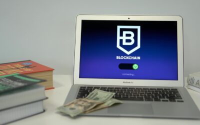 Laptop showing blockchain connection screen on desk with books and US dollars.