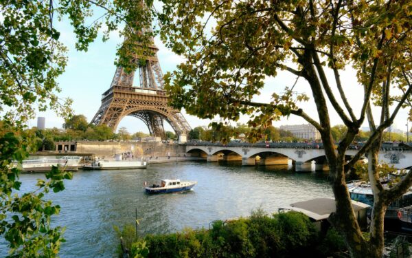 Captivating view of Eiffel Tower over Seine River with lush trees in Paris, France.