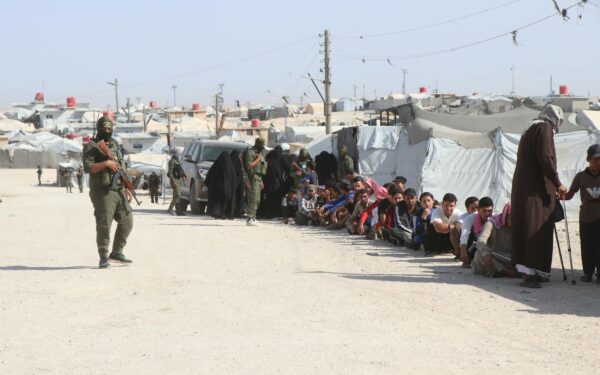 Refugees in al-Hol camp, Syria, guarded by soldiers, highlighting humanitarian crisis.