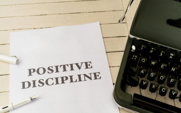 Vintage typewriter next to a paper with 'Positive Discipline' text, symbolizing communication and education.