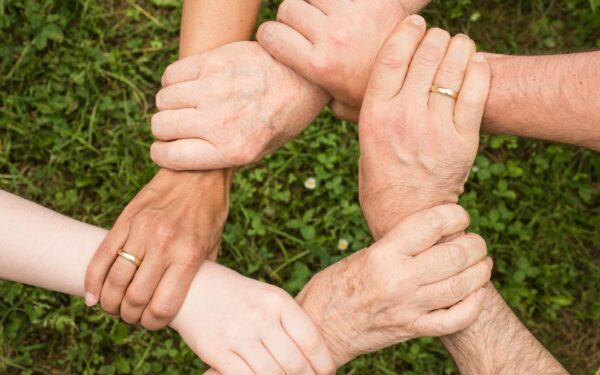 Close-up of diverse hands forming a connection, symbolizing teamwork and unity outdoors.