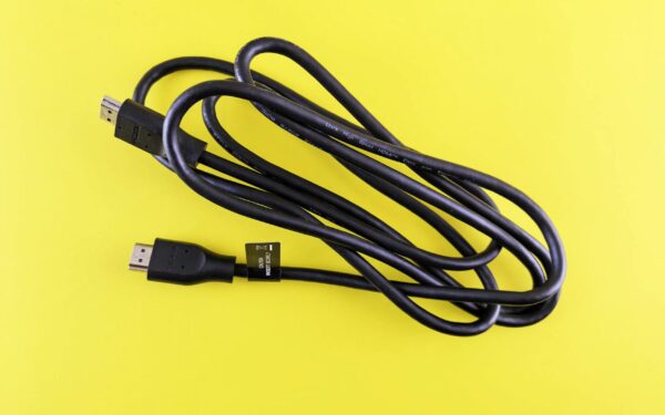 A neatly coiled black HDMI cable displayed on a vibrant yellow surface, ideal for tech visuals.