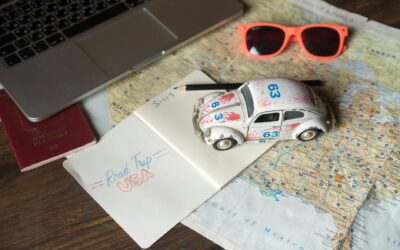 Flat lay of a road trip plan featuring maps, passport, toy car, and travel essentials.