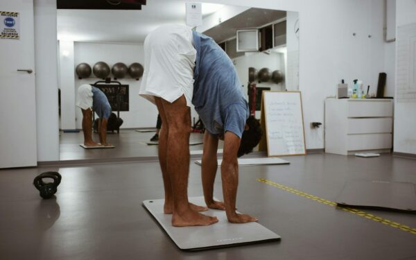 A man stretching on a gym mat with reflections in the mirror, promoting fitness health.