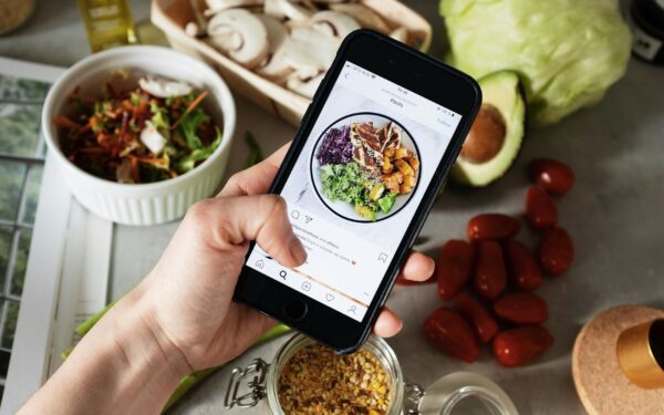 Person takes photo of healthy salad ingredients for social media in kitchen.