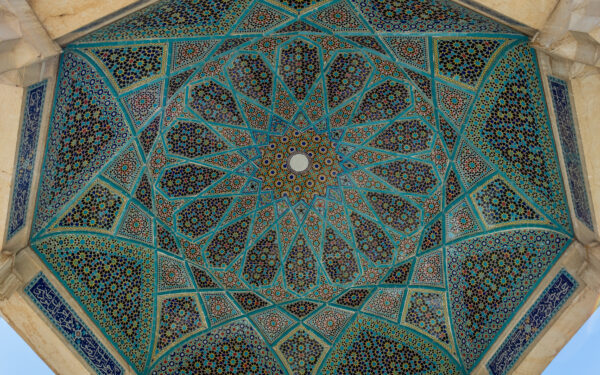 نمای آرامگاه حافظ شیرازی در میان باغ سرسبز حافظیه شیراز با ستون‌های سنگی